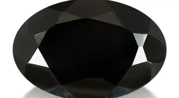 Espinela negra ovalada, facetada, con reflejos de luz que resaltan sus propiedades.