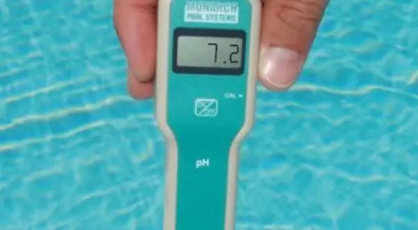Un appareil mesure le ph de l'eau d'une piscine. L'écran affiche 7.2, un niveau idéal pour la baignade.