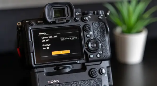 Tył aparatu Sony z ekranem pokazującym wersję oprogramowania korpusu i obiektywu.