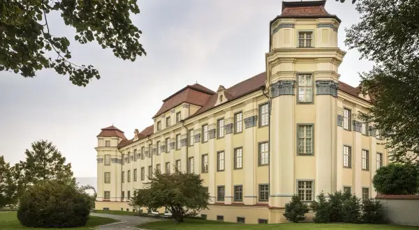 Das neue Schloss Tettnang erstrahlt in hellem Gelb mit roten Dächern. Ein Weg führt durch den gepflegten Garten.