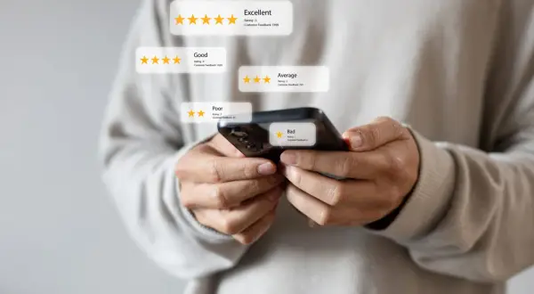 Osoba trzymająca smartfon sprawdza opinie o firmie, analizując oceny od "Bad" do "Excellent". To pokazuje, jak sprawdzić wierzytelność firmy.