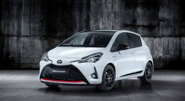Biały Toyota Yaris GR Sport z czarnym dachem i czerwonymi akcentami, zaparkowany na tle betonowej ściany.