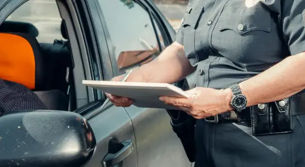 Policjant spisuje dane podczas kontroli drogowej. Widoczna rejestracja kk.