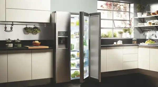 Cuisine moderne avec réfrigérateur ouvert, rempli de produits frais. L'inconvénient froid statique est évité grâce à une organisation optimale.