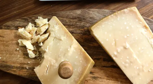 Due pezzi di formaggio stagionato, uno con scaglie e un piccolo tappo di legno, mostrano la differenza tra Gran Biraghi e Grana Padano.