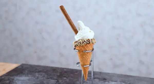 En mjukglass av vanlig glass, med strössel och en chokladpinne, serveras i ett krispigt våffelstrut.