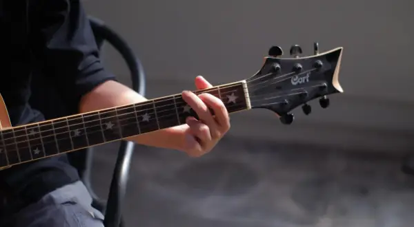 Dłoń grająca akord na gitarze klasycznej. Gwiazdki na gryfie dodają uroku, a całość przywodzi na myśl najładniejsze utwory na gitarę klasyczną.