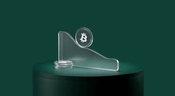 Kryptowaluty spadają, symbolizując co to bessa. Bitcoin na szczycie pochylonej platformy, obok stos monet.