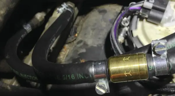 Złoty zawór zwrotny paliwa zamontowany na czarnym wężu paliwowym z oznaczeniem "FUEL INJECTION".