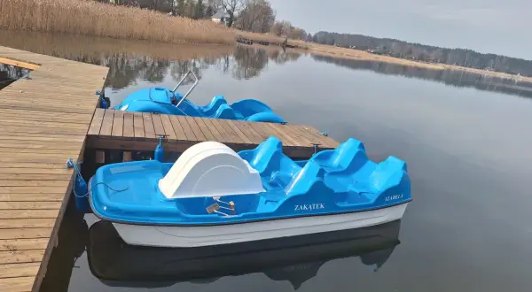 Błękitne rowerki wodne czekają na gości przy drewnianym pomoście. To idealne miejsce na wypoczynek, jak w słynnym polu namiotowym Sława.