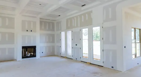 Interni di una casa in costruzione, con pareti e soffitto in cartongesso pronti per essere stuccati. Si intravede un camino.