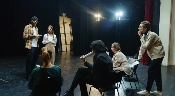Aktorzy na próbie dyskutują o scenariuszu, zastanawiając się, ile zarabia aktor za dzień zdjęciowy.