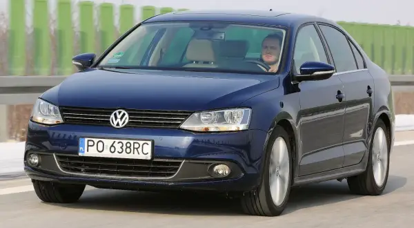 Ciemnoniebieski VW Jetta MK6 jedzie po autostradzie. Kierowca patrzy przed siebie.