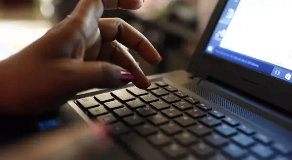 Dłoń z czerwonymi paznokciami pisze na klawiaturze laptopa. Może właśnie wpisuje swój kod podatkowy.