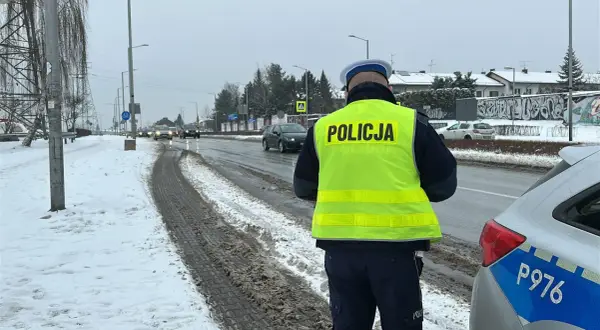 Policjant w kamizelce odblaskowej nadzoruje ruch drogowy w zimowych warunkach. Bezpieczne prowadzenie pojazdu to priorytet.