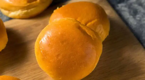 Pains à burger maison dorés et moelleux sur une planche en bois.