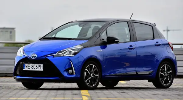 Niebieska Toyota Yaris Hybrid z czarnym dachem, zaparkowana na zewnątrz.