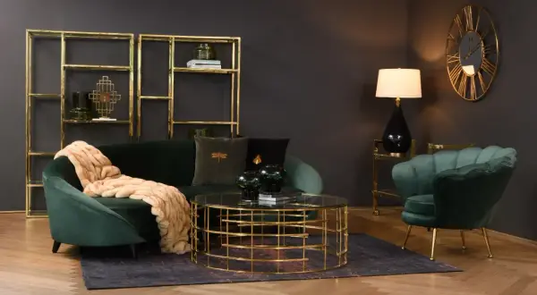 Butelkowa zieleń w salonie: aksamitna sofa i fotel, złote regały i stolik kawowy tworzą elegancką całość.
