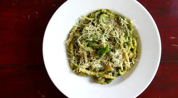 Assiette de trofie au pesto, garnie de parmesan râpé. Une recette italienne savoureuse et colorée.