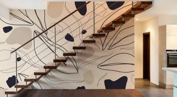 Escalier moderne avec un mur à l'effet peinture, orné de formes abstraites et de lignes organiques dans des tons neutres.