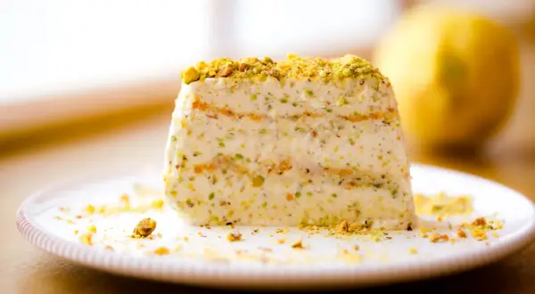 Ein Stück cremiges Semifreddo al Pistacchio, bestreut mit gehackten Pistazien, auf einem Teller.