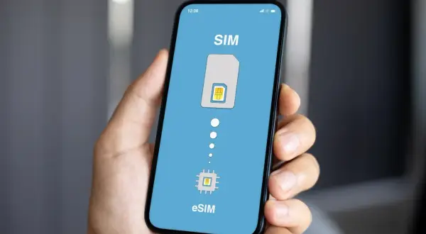 Dłoń trzyma smartfon z ekranem pokazującym przejście od tradycyjnej karty SIM do eSIM. Idealne rozwiązanie na kartę SIM internet za granicą.