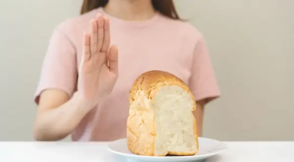 Kobieta odrzuca chleb, symbolizując dietę bezglutenową.
