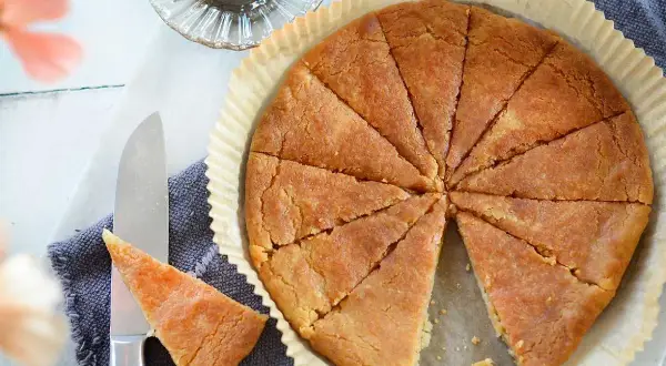 En gyllene, uppskuren kolakaka i en form. Ett recept på kolakakor som ser ljuvligt ut. En ljuslykta och en kniv med en bit kaka.