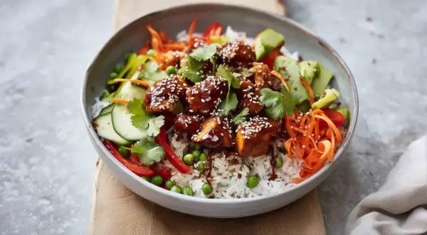 Pyszny bowl z kurczakiem w sosie teriyaki, ryżem, chrupiącą marchewką, ogórkiem, groszkiem i papryką.