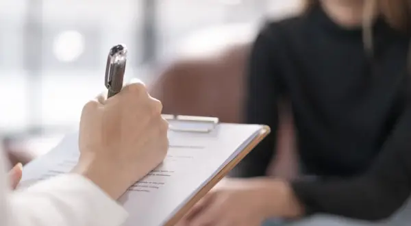Psycholog prowadzi diagnozę różnicową, notując spostrzeżenia podczas rozmowy z pacjentem.