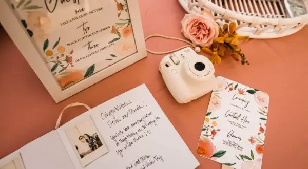 Wpis do księgi gości z polaroidami i życzeniami. Aparat Instax czeka na uwiecznienie chwil.