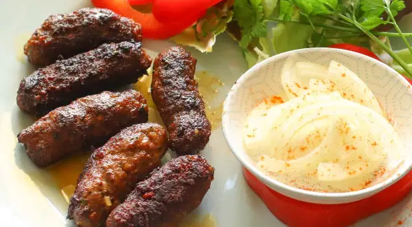 Saftige Cevapcici, perfekt gegrillt, serviert mit Zwiebeln und Salat. Ein tolles Cevapcici Rezept für jeden Anlass.