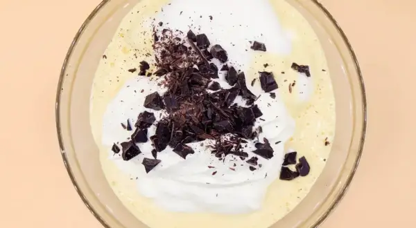 Mieszanka kremu, bitej śmietany i kawałków gorzkiej czekolady, gotowa do zamrożenia jako pyszne lody straciatella.