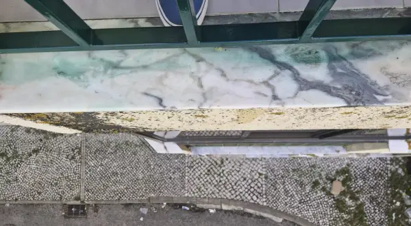 Come togliere la vernice dal marmo: una macchia verde su un davanzale di marmo, con scarpe blu in primo piano.