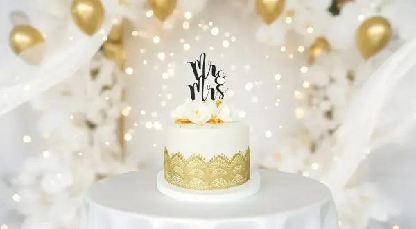 Elegancki tort weselny z napisem "Mr & Mrs" i złotymi zdobieniami. Idealne miejsce, gdzie kupić ozdoby na tort na wyjątkowe okazje.