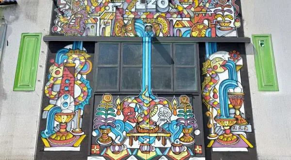 Mural colorato con il nome "LZO Brewery" in alto, raffigurante creature fantastiche, cascate e simboli.