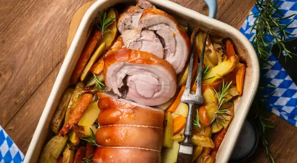 Saftiger **Rollbraten im Backofen** mit knusprigen Kartoffeln und Karotten, garniert mit Rosmarin. Ein Festmahl!