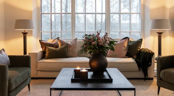 Mysig lounge med soffa och gröna artwood fåtöljer. Blommor, ljus och en filt skapar en varm atmosfär.