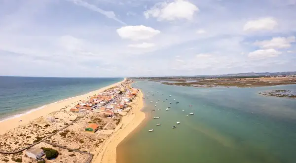Faro: Was tun? Eine Küstenstadt mit Sandstrand, Häusern und vielen Booten im Wasser. Perfekt für einen entspannten Urlaub.