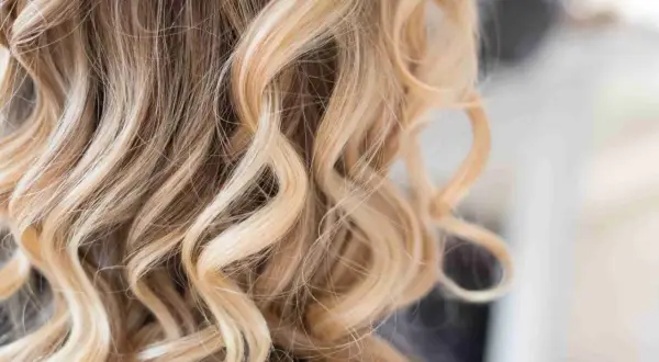 Falujące, blond włosy z subtelnymi, ciemnymi pasemkami, tworzącymi naturalny efekt.