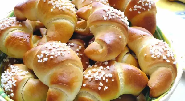 Koszyk pełen mięciutkich rogalików drożdżowych, posypanych cukrem. Idealne na śniadanie, zgodnie z prostym mięciutkie rogaliki drożdżowe przepis.