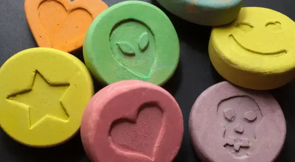 Kolorowe tabletki z symbolami: serce, gwiazda, kosmita, uśmiech, czaszka.