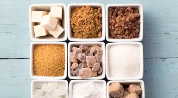Neuf carrés blancs remplis de différents types de sucre : cubes blancs, cassonade, sucre candi, etc.