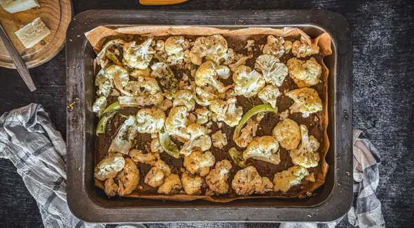Goldbrauner blumenkohl im backofen, knusprig und aromatisch, bereit zum Genießen. Daneben ein Stück Käse und ein Dip.