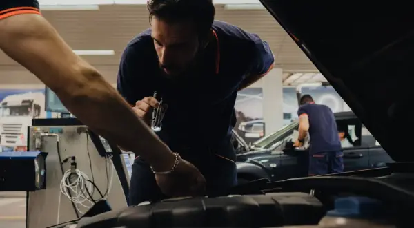 Mecánicos revisan un coche en un taller, asegurándose de que todo esté perfecto cuando se pasa la primera ITV.