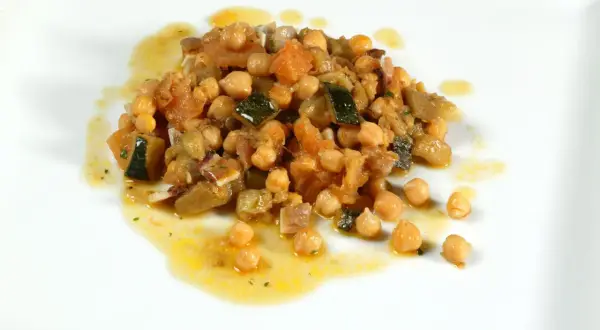 Deliciosos garbanzos con pisto, una mezcla colorida de verduras y legumbres en un plato blanco.