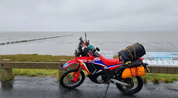 Czerwony motocykl przygotowany na podróż motocyklem nad morze, zapakowany i gotowy do drogi.