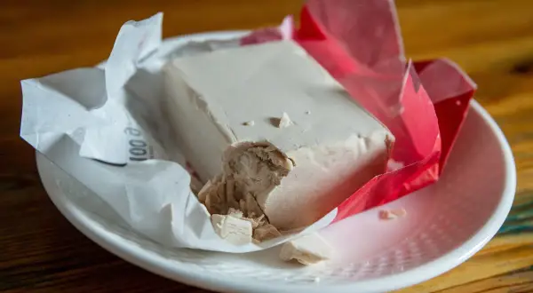 Kostka świeżych drożdży na talerzyku. Zastanawiasz się, czy drożdże można mrozić? Tak, można je zamrozić, by zachować ich świeżość na dłużej.