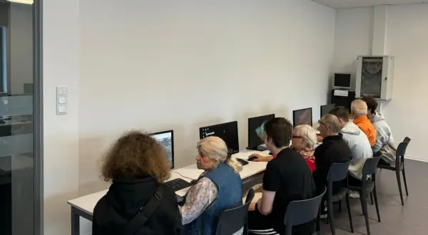 Grupa osób w różnym wieku uczy się obsługi komputera. To idealny przykład, co to zajęcia z samorozwoju dla każdego.