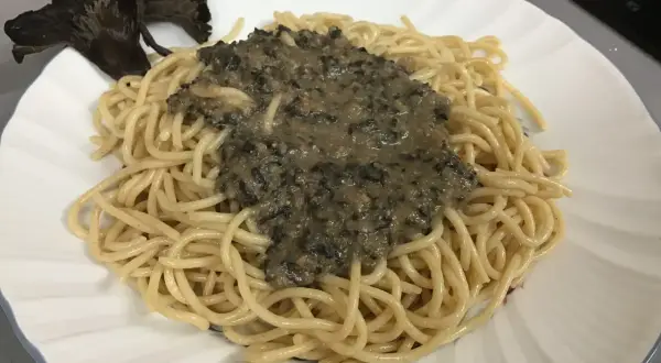 Deliciosa pasta con una cremosa salsa de trompetas de la muerte y un hongo entero como decoración.